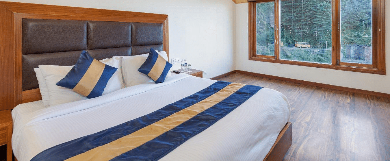 Image o a large, comfortable-looking bed with a headboard and a window overlooking the mountains | DLS Serenity Resort and Spa